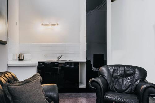 a living room with two chairs and a kitchen at Albert Hotel Daylesford in Daylesford