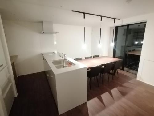 a kitchen with a sink and a table with chairs at Fujio Pension Madarao Apartment Hotel & Restaurant in Iiyama