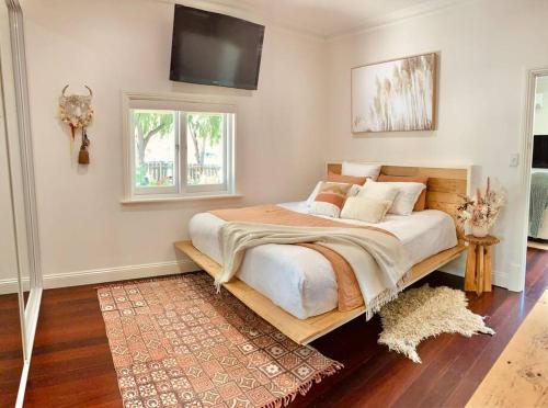 ein Schlafzimmer mit einem großen Bett und einem Flachbild-TV in der Unterkunft Laurant's Cottage ~ McLaren Vale entertainer in McLaren Vale