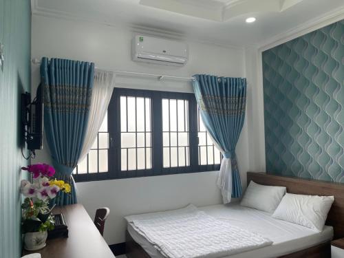 a bedroom with a bed with blue curtains and a window at Kim Ngân Motel in Chau Doc
