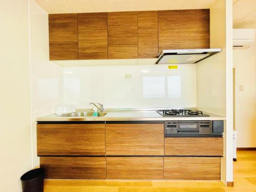 a kitchen with wooden cabinets and a sink at Uhome Kamogawa 本館-【ペット可/広い2LDK】 in Kamogawa