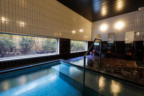Temple Town Hotel WAQOO Horyuji في Ikaruga: مسبح في مبنى مع نافذة كبيرة