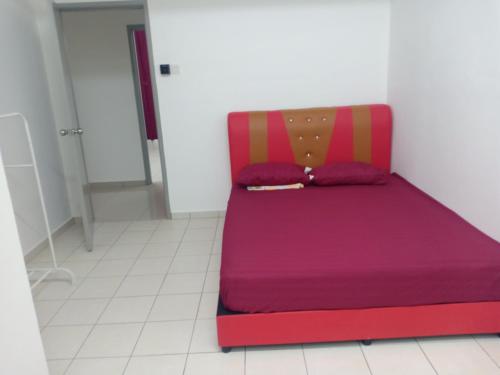 uma cama vermelha com lençóis e almofadas roxos num quarto em Alea Homestay Taman Tasik Utama MiTC em Ayer Keroh