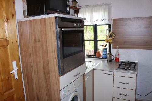 a kitchen with a stove and a microwave at Глинената къща в Дълги Дел in Dŭlgi Del