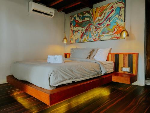 a bed in a room with a painting on the wall at Seascapes Bira in Bira