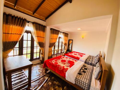 a bedroom with a bed and a table and windows at travellers nest inn in Nuwara Eliya