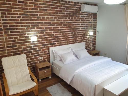 um quarto com uma parede de tijolos, uma cama e uma cadeira. em Shkodra 27 center house em Shkodër