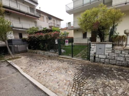 a fence in front of a building with a street at La Gabbianella in Marcelli