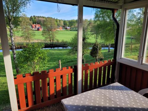 een afgeschermde veranda met een tafel en uitzicht op een veld bij Sommarstuga in Vårgårda