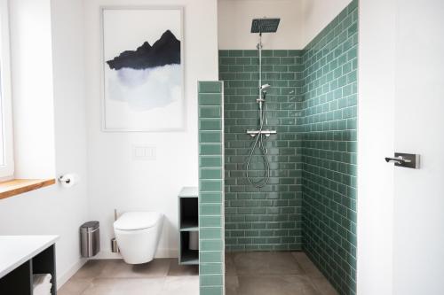 baño con ducha con azulejos verdes de metro en Moderne neue Apartments zum Wohlfühlen im Boardinghouse bed & butter, en Hasbergen
