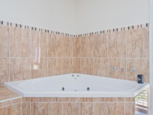 a white bath tub in a tiled bathroom at Snowy Mountains Retreat in Moonbah