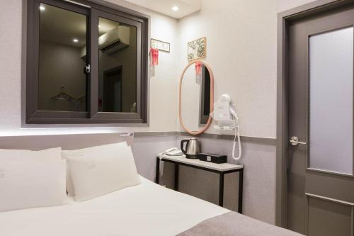 a bedroom with a white bed and a mirror at Hotel dongyangjang Dongdaemun-Jongno in Seoul