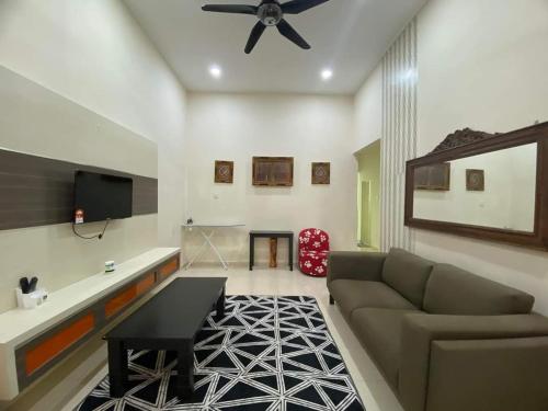 a living room with a couch and a ceiling fan at Nice and cozy house in Muar in Muar