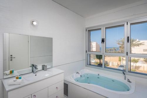 a white bathroom with a tub and a sink at וילה לגון in Netanya