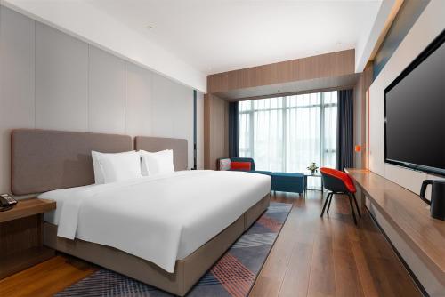 um quarto de hotel com uma cama grande e uma televisão de ecrã plano em Holiday Inn Express Nanning Convention&Exhibition em Nanning