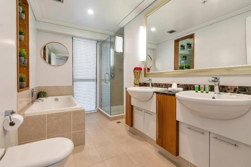 a bathroom with two sinks and a tub and a toilet at Sunset Harbour Sanctuary + CP in Auckland