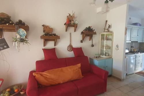 sala de estar con sofá rojo y cocina en Residenza Anna, en Montemerano