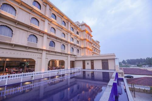 a large building with a swimming pool in front of it at Regenta Central City Vilas Palace Ambala in Ambāla