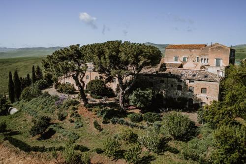 une vieille maison sur une colline avec des arbres et des buissons dans l'établissement Antico Feudo San Giorgio, à Polizzi Generosa