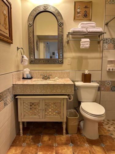 a bathroom with a sink and a toilet and a mirror at El Amador Inn Downtown Tucson in Tucson