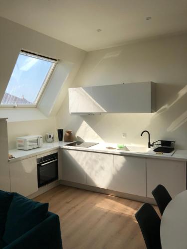 una cocina con encimeras blancas y una ventana en Appartement vue bassin 2 chambres en Arcachon