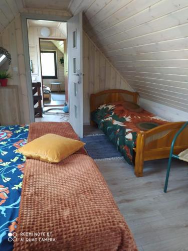 a attic bedroom with two beds and a hallway at Agroturystyka Giże - domek letni in Ełk