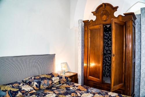 a bedroom with a bed and a wooden cabinet at MIMAR Casa Vacanze Charme ed Eleganza in Maruggio