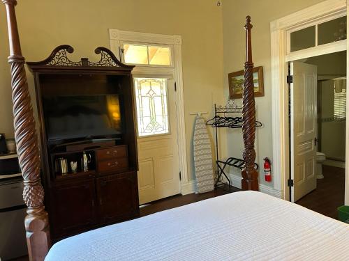 a bedroom with a bed and a dresser with a television at El Amador Inn Downtown Tucson in Tucson