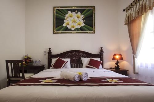 a bedroom with a bed with a flower picture on the wall at Frangipani Homestay in Nusa Dua