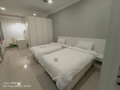 a white bedroom with a large bed with white sheets at Peace home09 in Cyberjaya