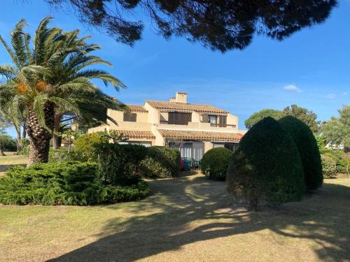 una casa grande con palmeras y arbustos en Grand studio entre le golf et la plage à 800m en Saint-Cyprien-Plage