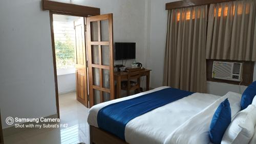 a bedroom with a bed and a television and a window at The Camellia in Dibrugarh