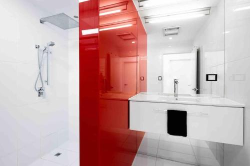 baño con lavabo blanco y pared roja en Scarborough Waterfront Penthouse Unit en Scarborough