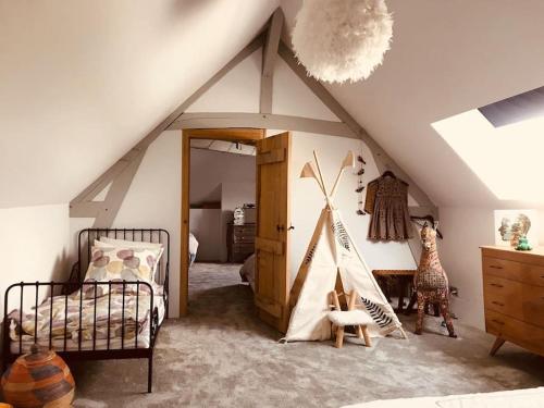 Cette chambre mansardée comprend un lit et un lit bébé. dans l'établissement Grande Maison en bord de Seine, 1h 15de Paris, à Muids