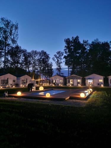 - une vue nocturne sur une allée avec des lumières la nuit dans l'établissement Lumi Resort Domki letniskowe z podgrzewanym basenem, à Rewal