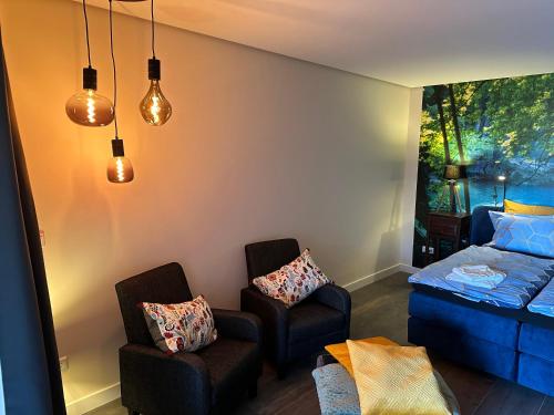 a bedroom with two chairs and a bed with a window at Bed&Breakfast de Hooimoat in Losser