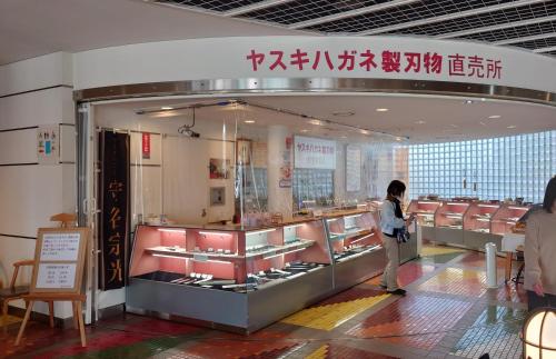 a woman standing in front of a store window at ゲストハウス あずも GuestHouse AZMO in Matsue