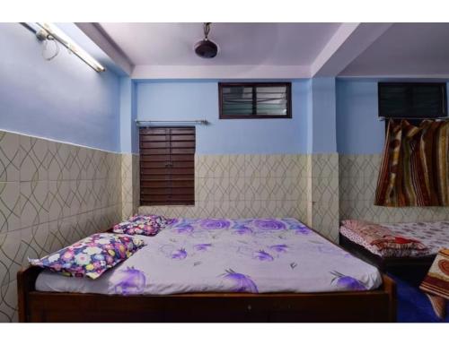 a bedroom with a bed with purple pillows on it at Alankar Lodge, Karagpur in Kharagpur
