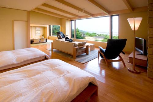 a bedroom with a bed and a couch and a television at 山荘 風の杜 Sanso Kazenomori in Minoo