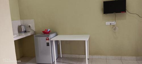 a white table and a small refrigerator in a room at ALZA BUDGET ROOMStay in Pantai Cenang