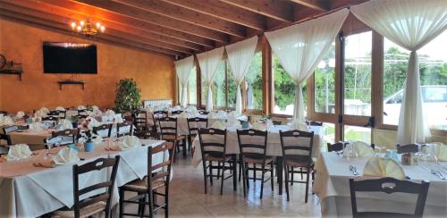 una sala de banquetes con mesas y sillas blancas y TV en Agriturismo Il Pavone en Torre Lapillo