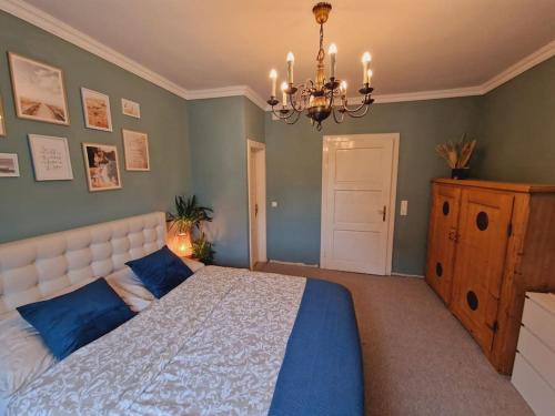 Un dormitorio con una cama con almohadas azules y una lámpara de araña. en Casa Lucia, en Knittelfeld