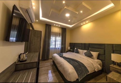 a bedroom with a large bed and a television at Fragrant Rose in Wadi Musa