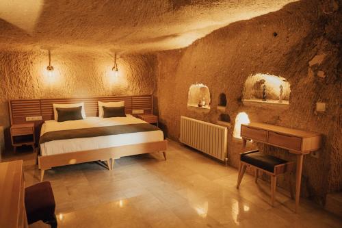 a bedroom with a bed and a piano in a cave at Juno Cappadocia Adults Only in Uchisar