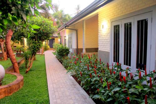 a garden with red flowers next to a house at Morning Star Resorts in Negombo