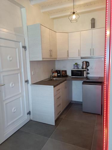 a small kitchen with white cabinets and a microwave at The Muses of Santorini Private Jacuzzi Suites in Vóthon