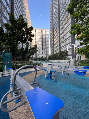 a row of benches in a park with tall buildings at The Heim in Kajang