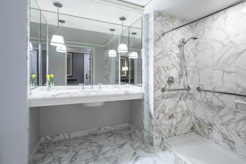 een witte badkamer met een wastafel en een douche bij The Ritz-Carlton, St. Louis in Clayton