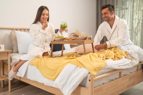 a man and woman in bath robes sitting on a bed at Amaris - Apartamente la Plajă Eforie Nord in Eforie Nord