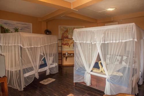 two beds in a room with white curtains at Ravana Range Ella in Ella